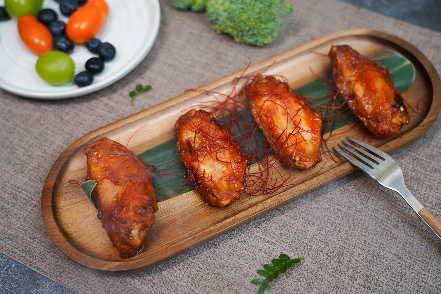 Delicious spicy grilled chicken wings served with fresh fruits for a delightful meal.