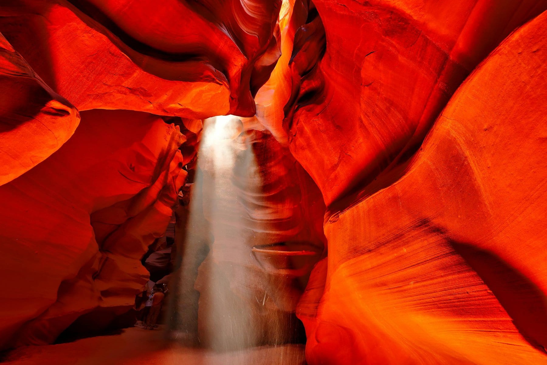 Dramatic sunlight beams illuminate the vibrant red walls of Antelope Canyon, Arizona.