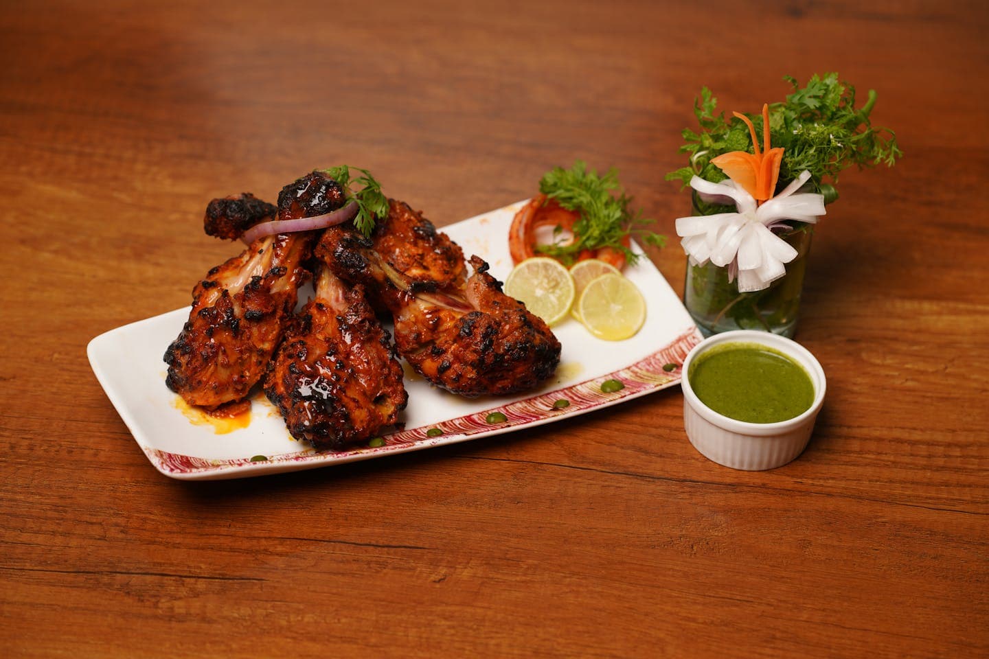 Juicy grilled chicken wings with green dipping sauce and fresh herbs, appetizingly presented.