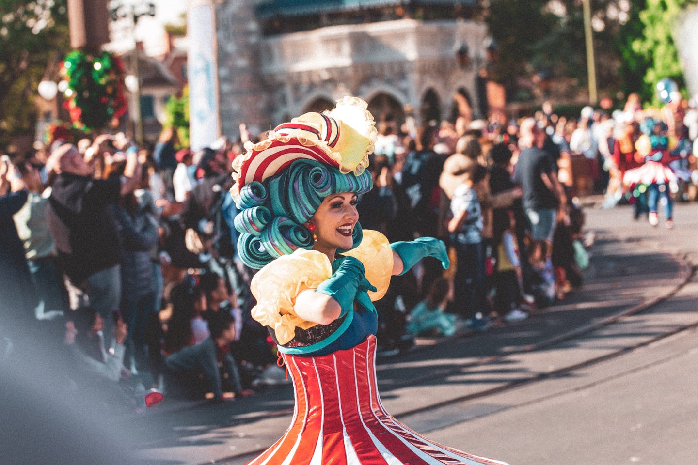 A lively performer in colorful costume entertains the crowd at a festival parade in Orlando.