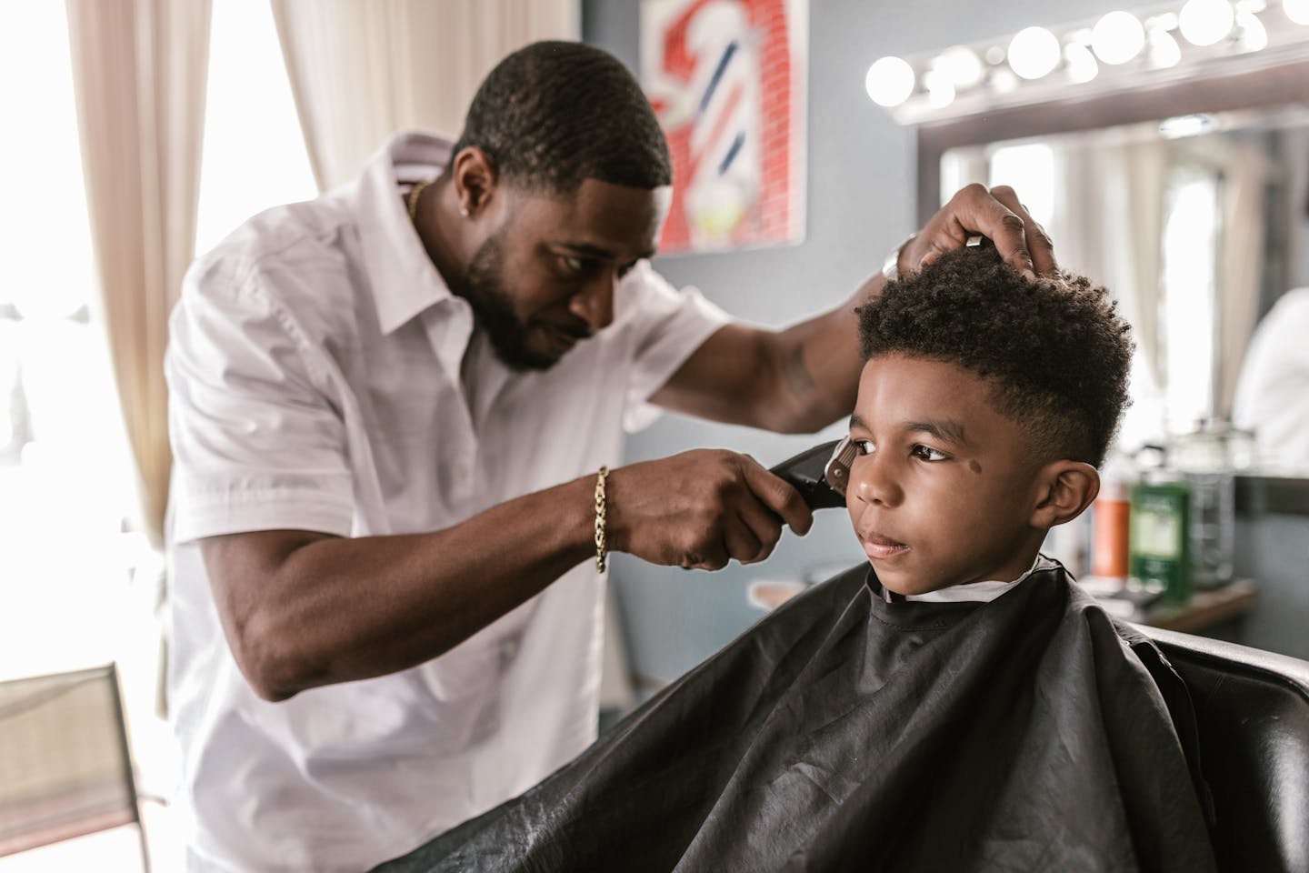 A skilled barber provides a stylish haircut to a young boy in a barber shop.