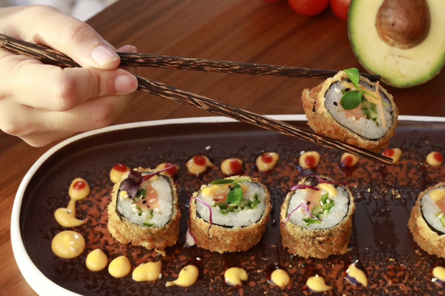 Close-up of delicious crispy sushi rolls with avocado on a platter.