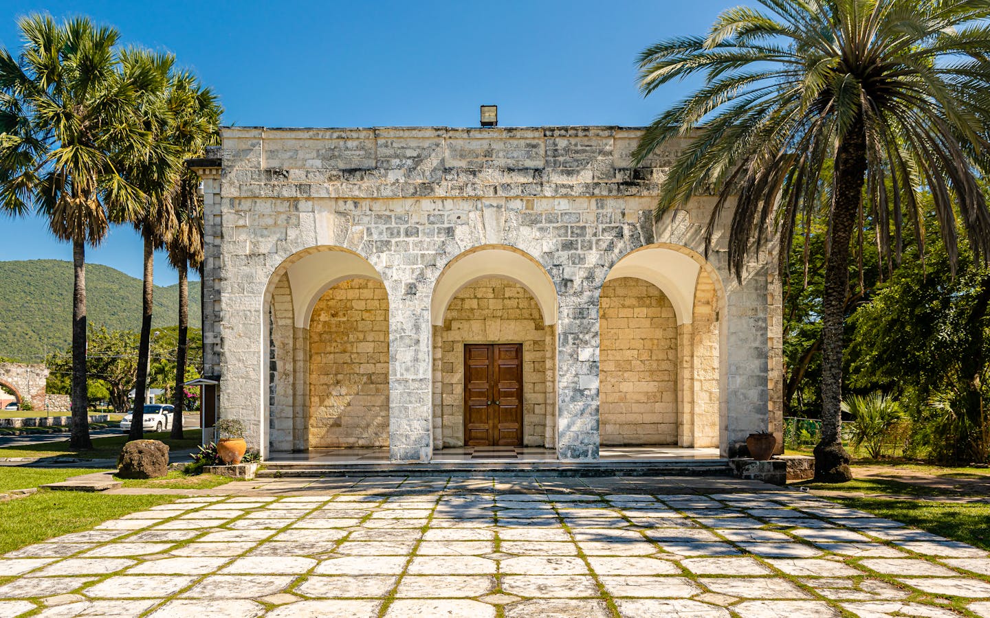 Old stone structure with arched entrance surrounded by palm trees in Kingston, Jamaica.