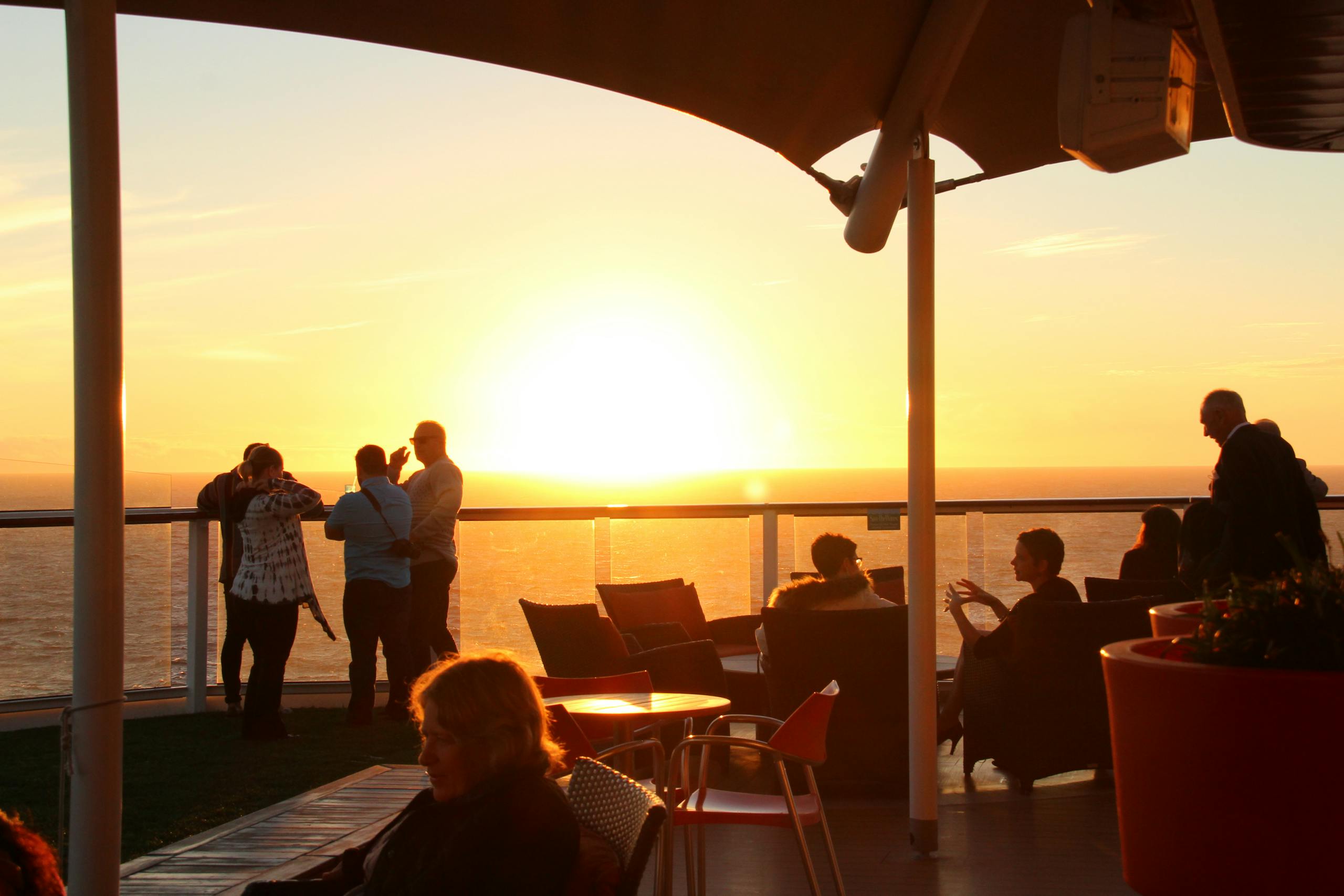 People enjoying a breathtaking ocean view during golden hour on a cruise ship deck.