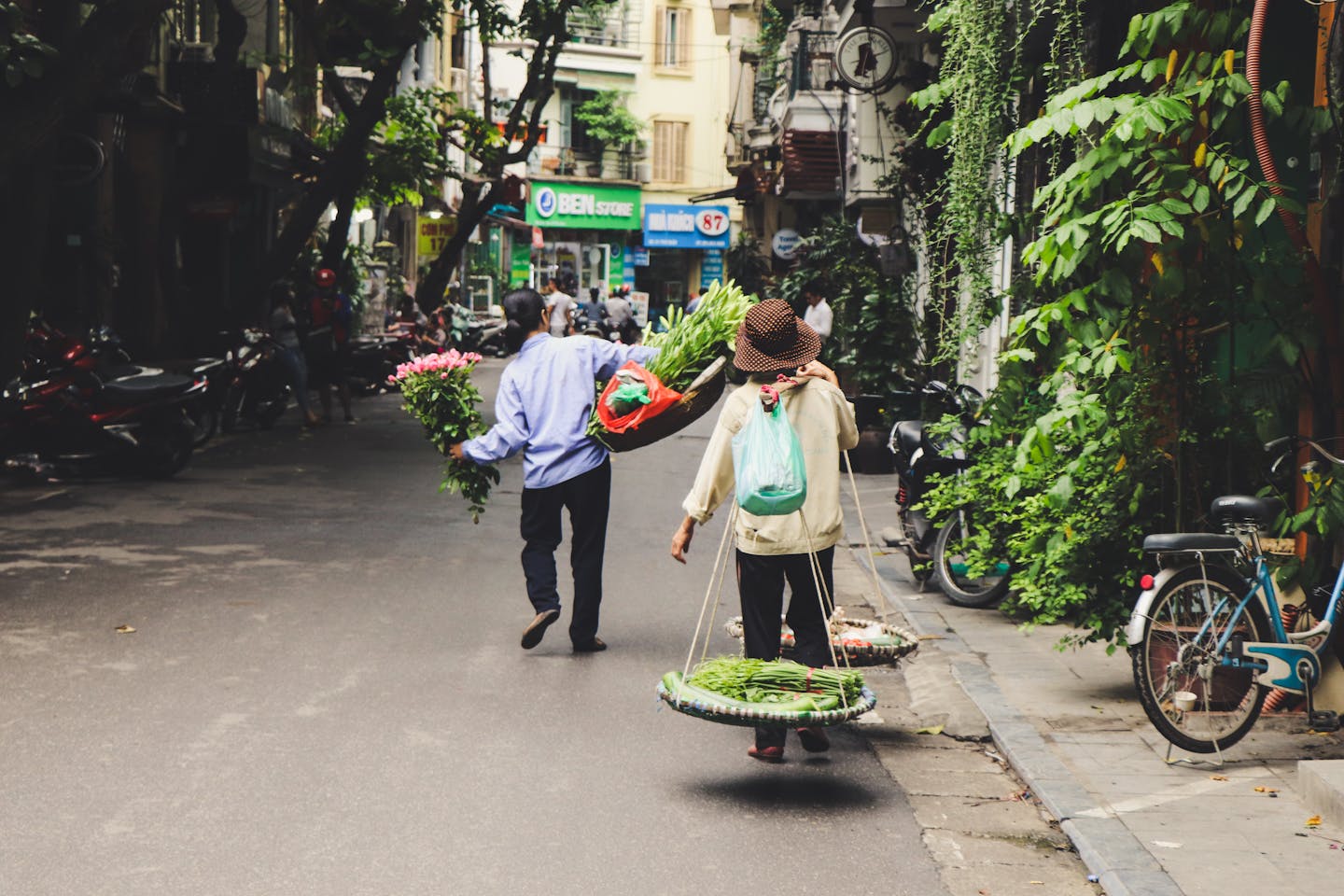 Street vendors in Hanoi, Vietnam, selling fresh vegetables and flowers on a vibrant local street.