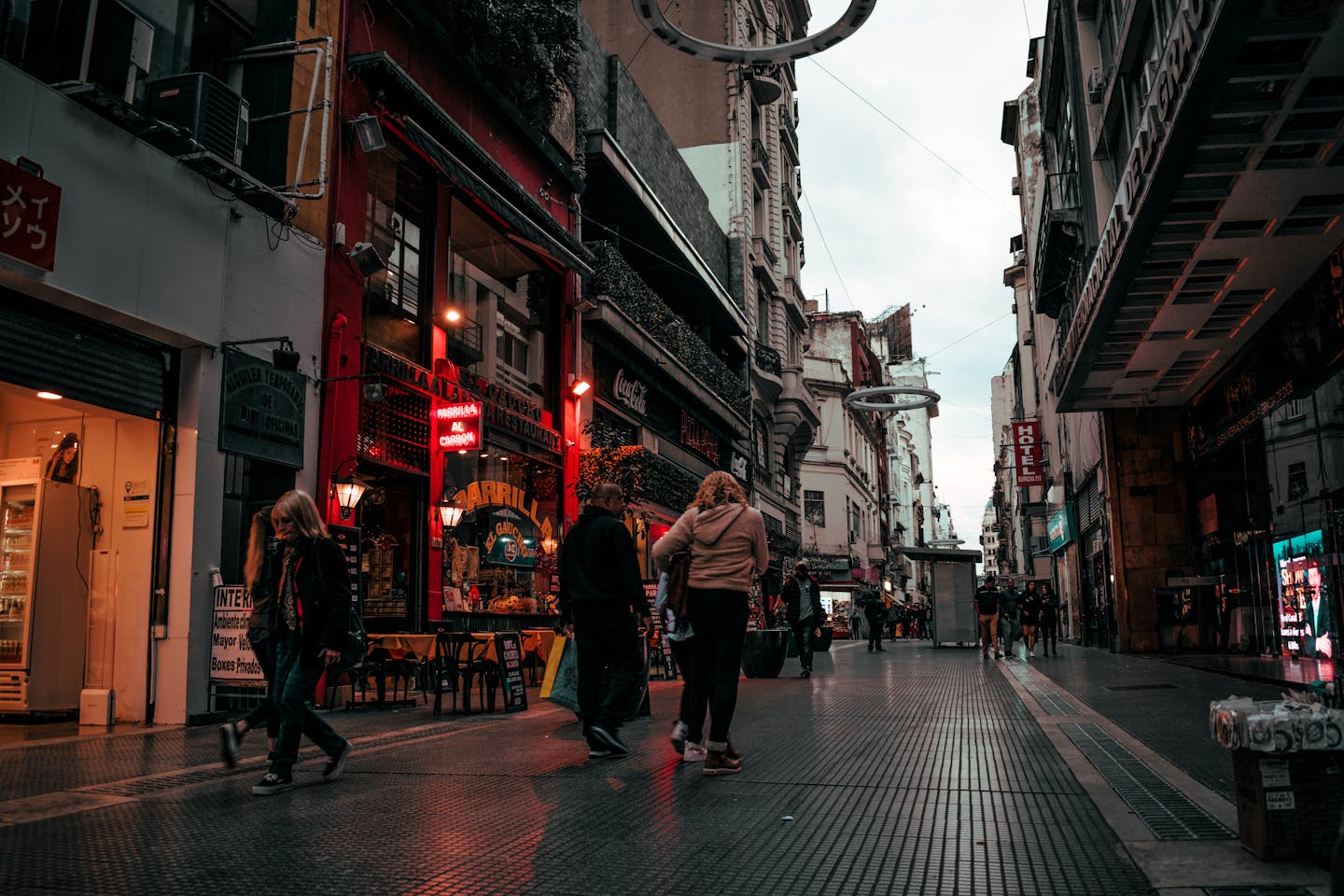 Street view of people walking in a vibrant Buenos Aires alley at dusk.