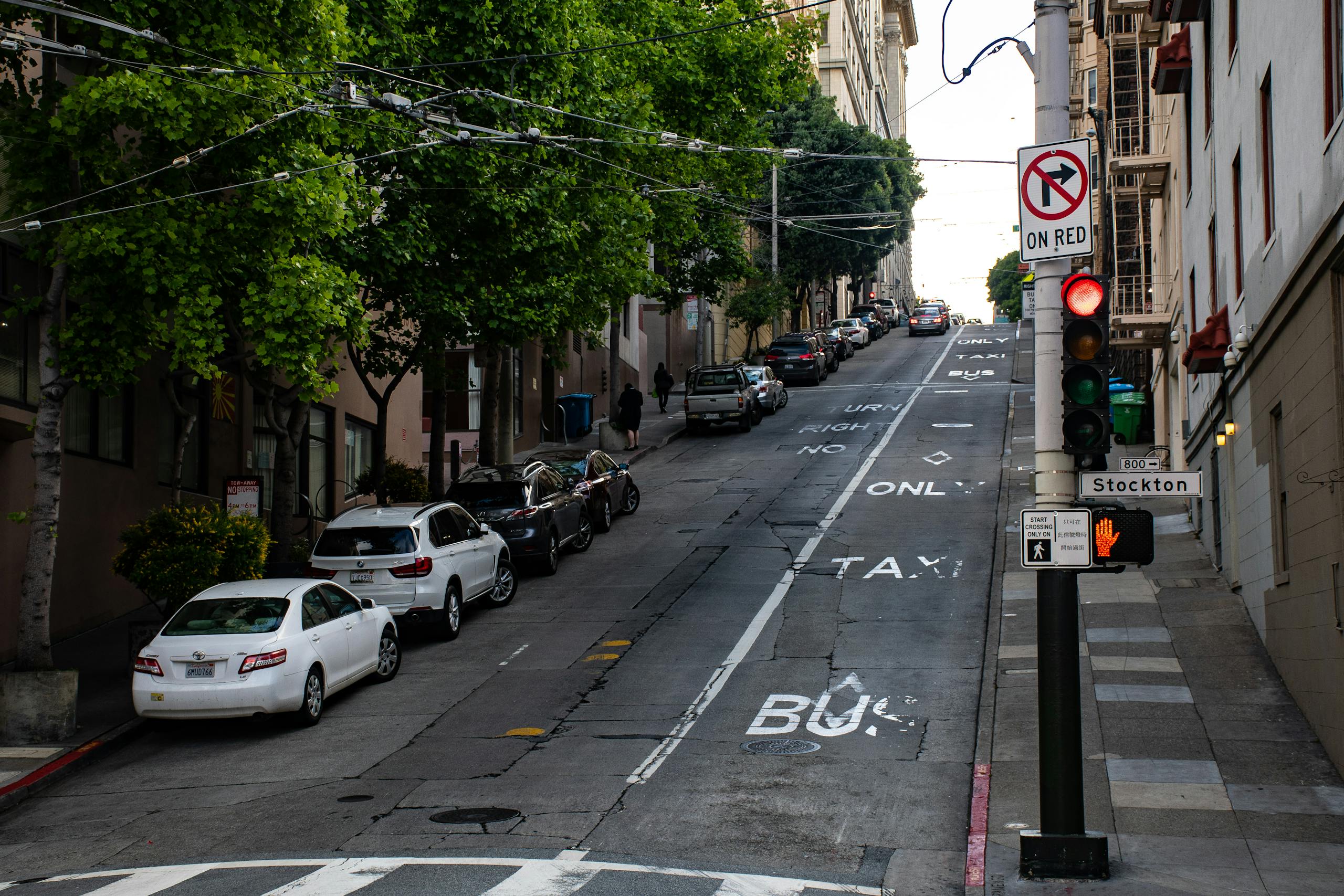 A steep urban street in San Francisco with parked cars and traffic signals, steep road