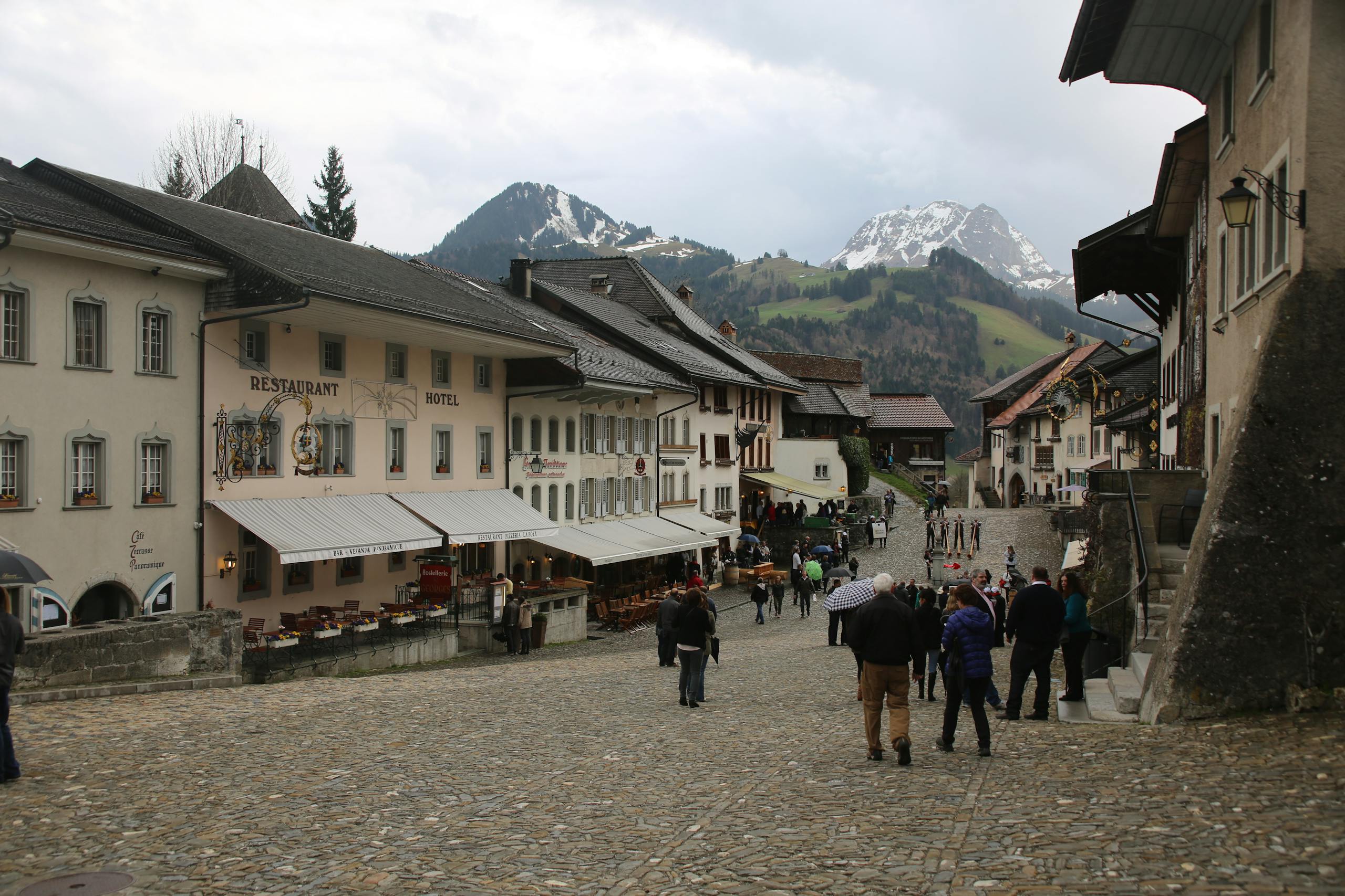 Charming village scene in Gruyères, Switzerland featuring cobblestone streets and the Swiss Alps.