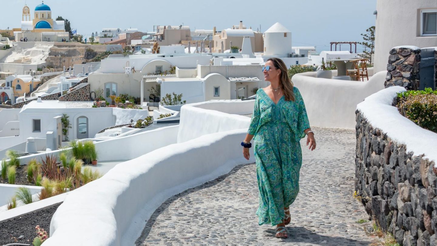 Explore the picturesque white architecture of Santorini with a woman enjoying a summer stroll.