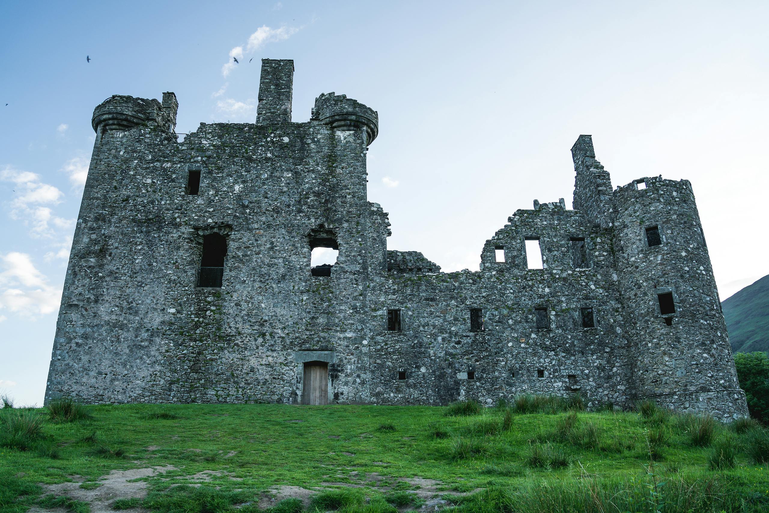 Scenic view of Kilchurn Castle ruins surrounded by grass, a testament to Scottish history.