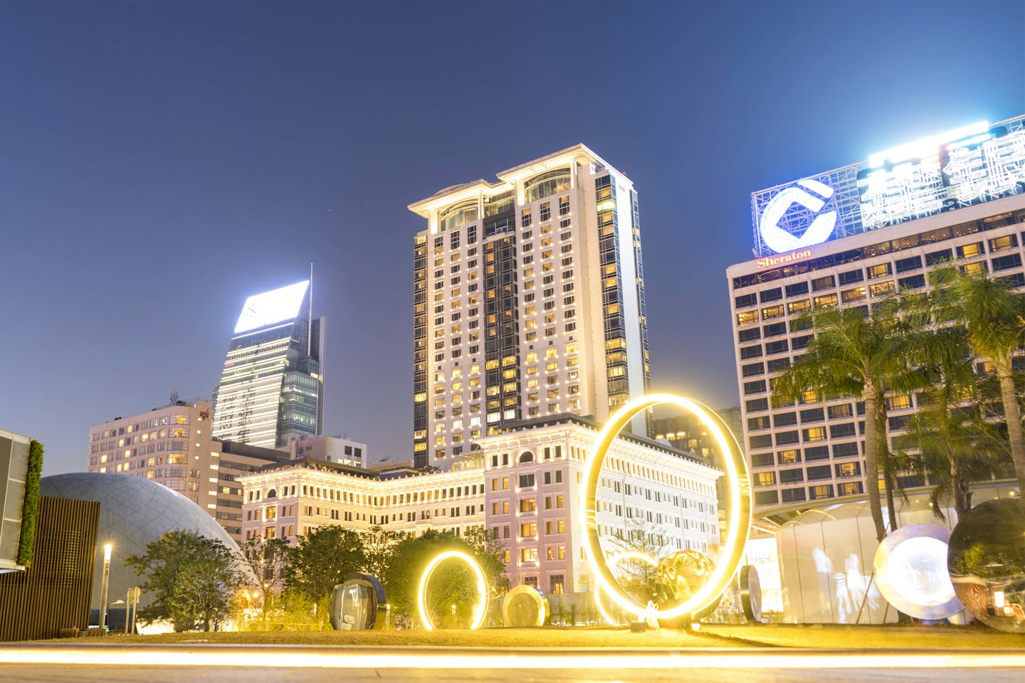 Stunning cityscape at night featuring modern architecture and illuminated light rings in an urban setting.