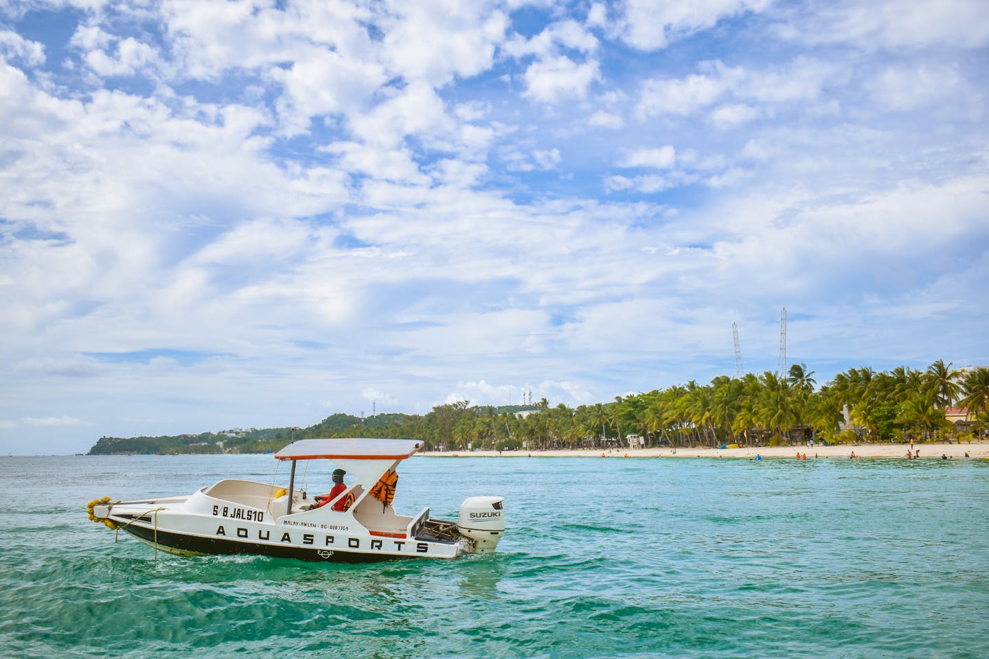 A bright summer scene showing a speedboat cruising near Boracay's white sand beach, Philippines.