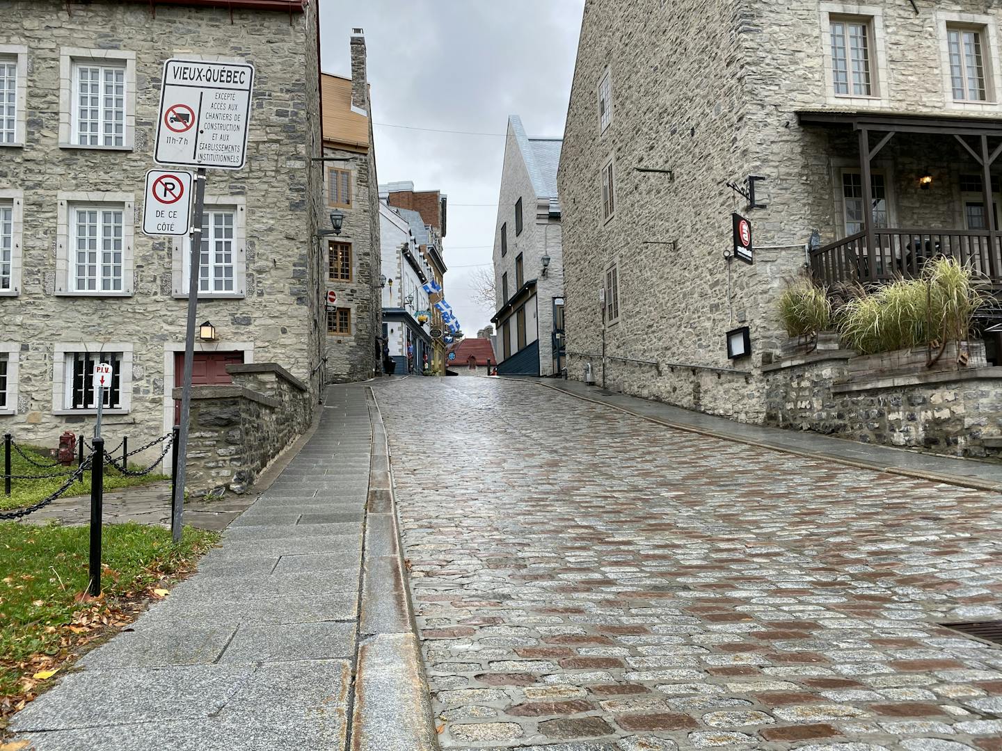 Charming cobbled street in Old Quebec City featuring historic stone buildings on a cloudy day.