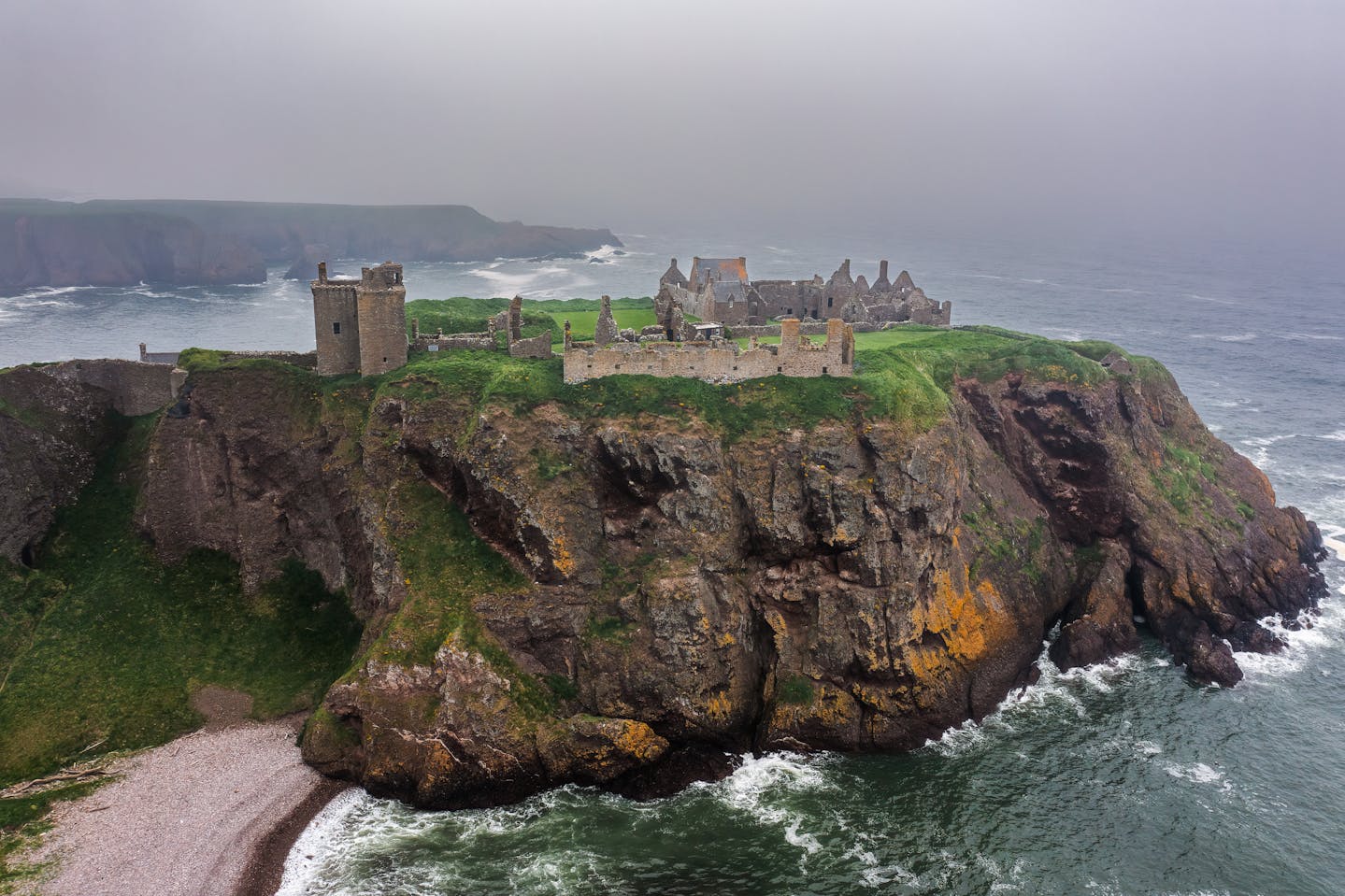 Drone capture of Dunnottar Castle perched on cliffs by the sea in Scotland.