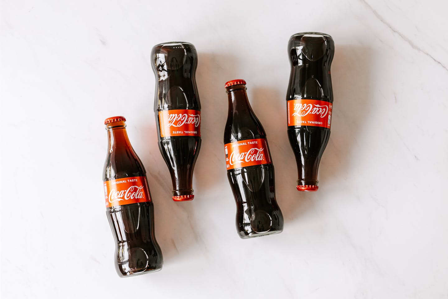 High angle composition of bottles of soft drink placed on white marble table