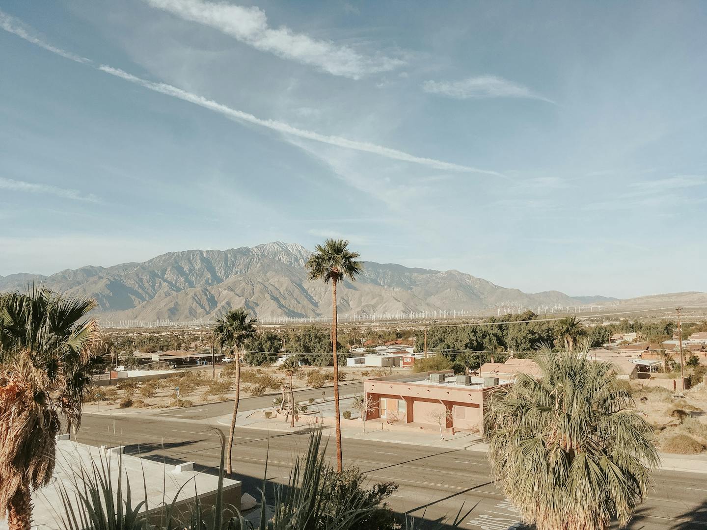 Stunning desert landscape in Palm Springs, CA, featuring mountains, palm trees, and clear skies.