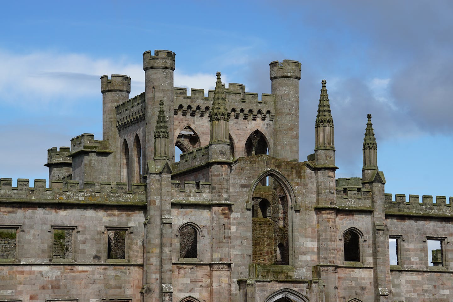 Stunning view of ancient castle ruins with gothic architecture under a clear blue sky.