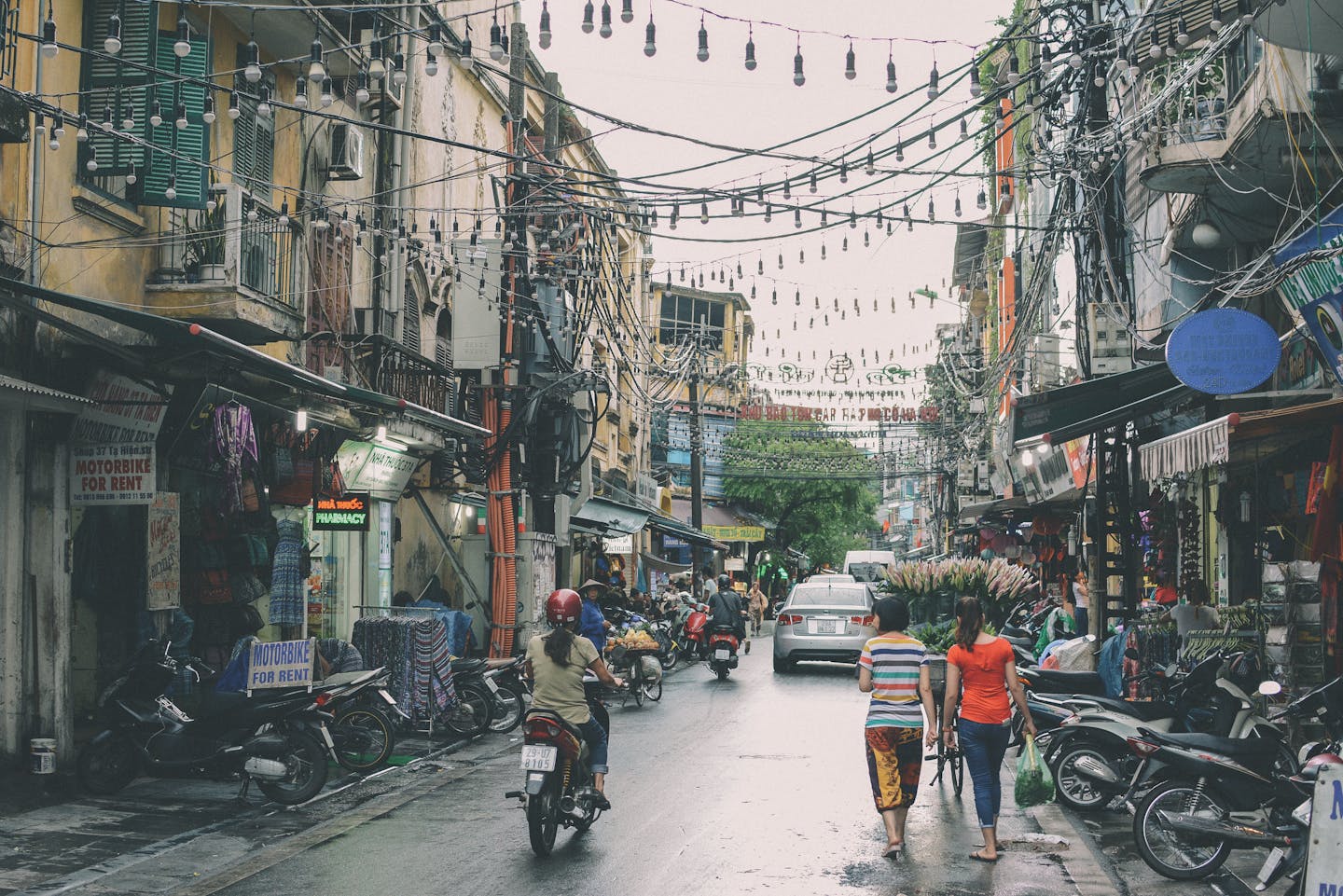 Vibrant street scene in Hanoi's Đống Đa district with bustling markets and motorbikes.
