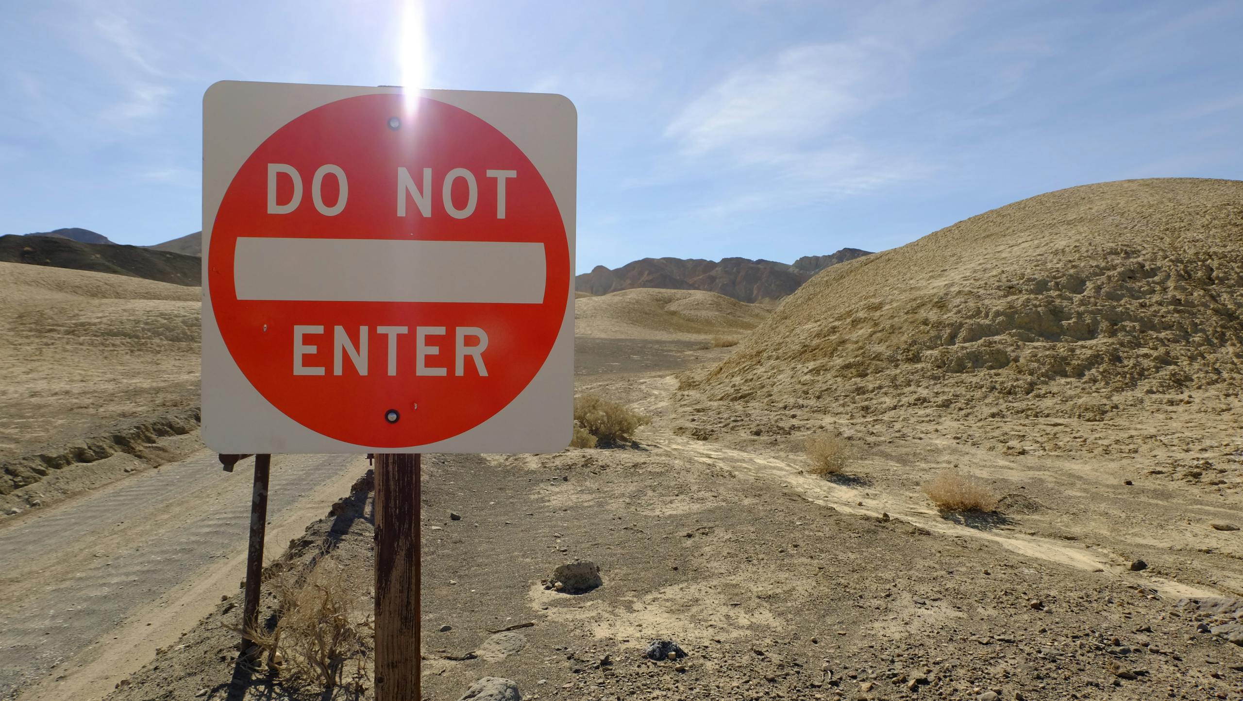 A 'Do Not Enter' sign in a desolate desert setting under a bright sky.