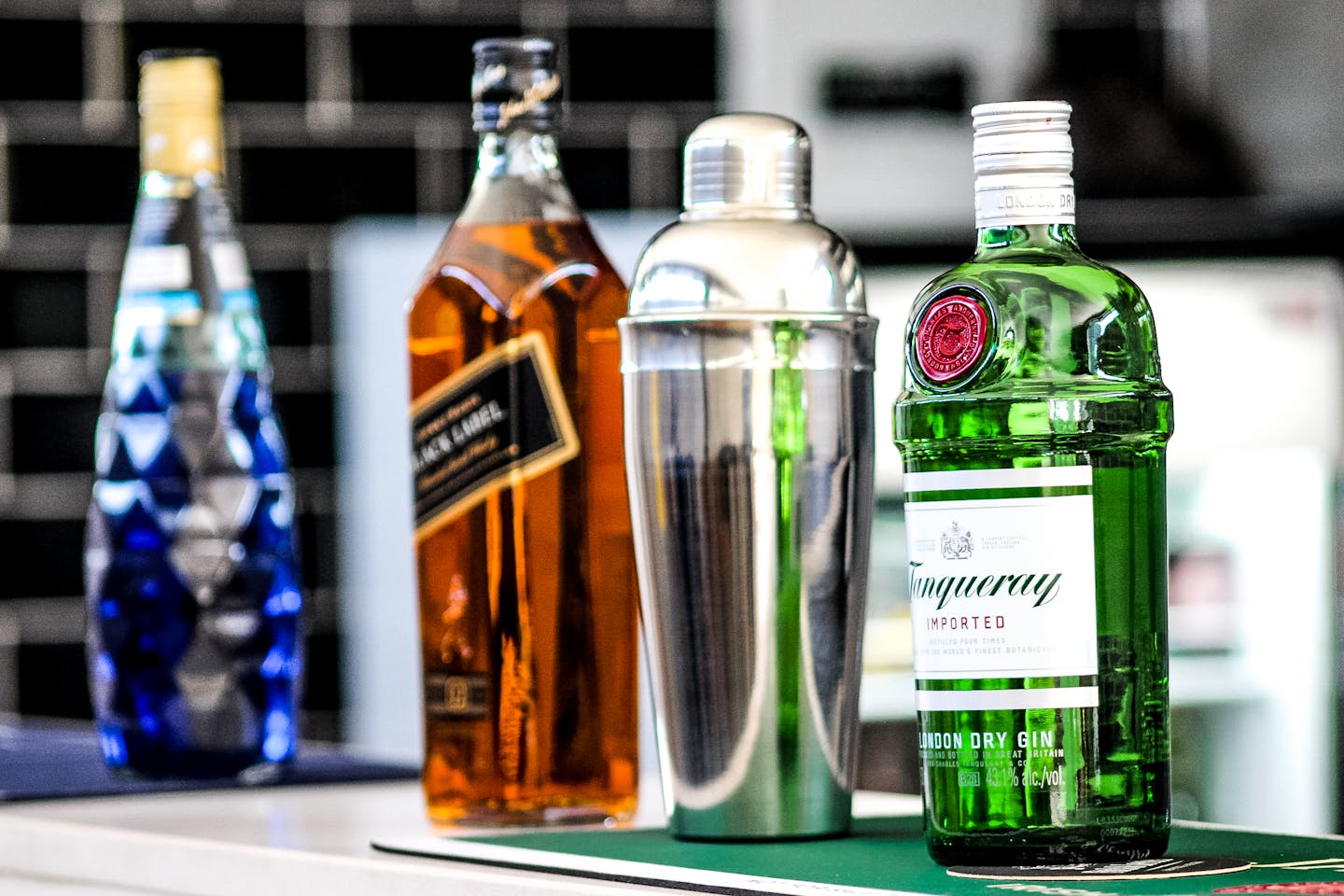 A selection of liquor bottles including gin, whiskey, and a cocktail shaker on display.