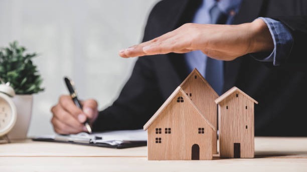 Insurance house, and family health live concept. The insurance agent presents the hands protection model that symbolize the coverage.