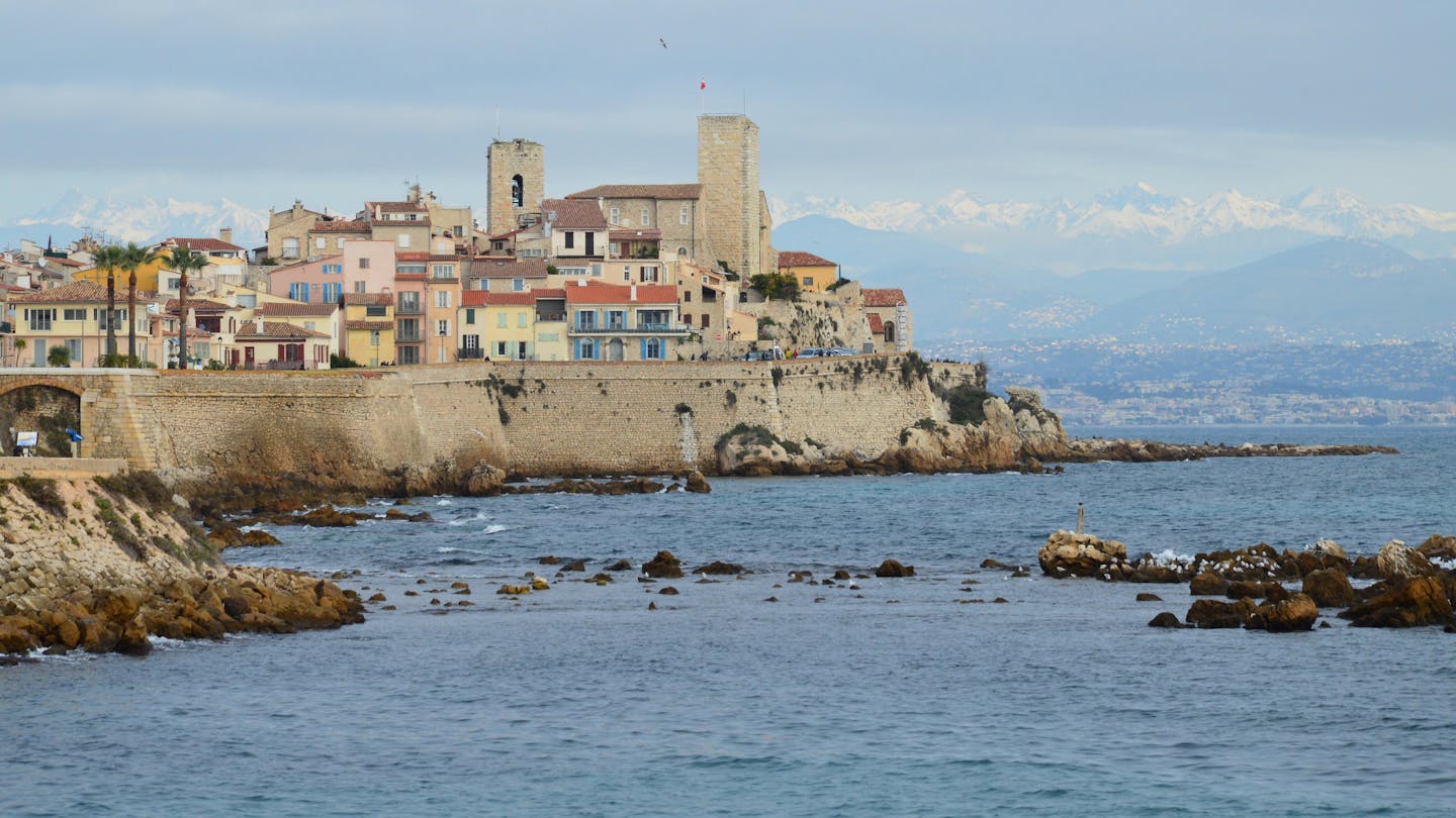 Beautiful coastline of Antibes with historic architecture and mountain backdrop.