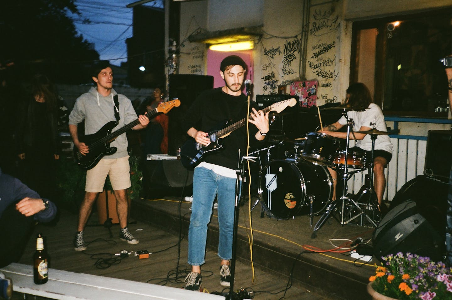 Energetic band playing music outdoors at night, showcasing guitars and drums.